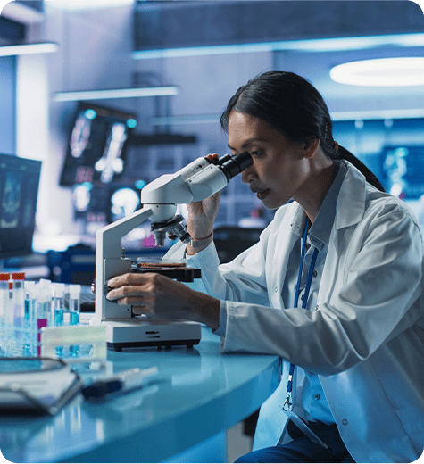 Scientist examining blood cancer samples under a microscope in a clinical research laboratory